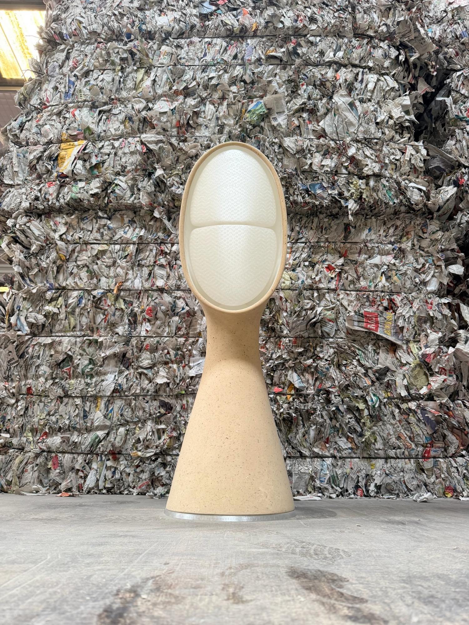 Lampe Amba 95 en papier recyclé, devant des balles de journaux